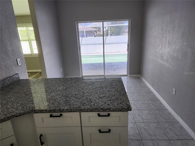 4354 Rock Creek Dr, Port Charlotte, FL 33948 - kitchen with white cabinetry, a textured wall, dark stone counters, and a peninsula