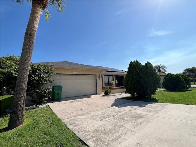 19358 Edgewater Dr, Port Charlotte, FL 33948 - view of front of home featuring concrete driveway, roof mounted solar panels, a garage, stucco siding, and a front yard
