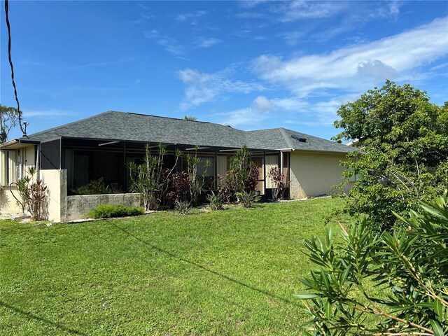 19358 Edgewater Dr, Port Charlotte, FL 33948 - rear view of house featuring a yard, a sunroom, a shingled roof, and stucco siding