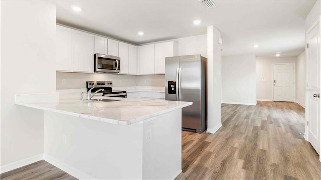 12039 Lansing Gln, Parrish, FL 34219 - kitchen featuring stainless steel appliances, light wood-style flooring, a peninsula, light stone countertops, and white cabinetry