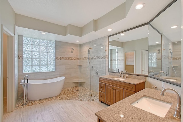 5080 Timber Chase Way, Sarasota, FL 34238 - bathroom featuring a stall shower, two vanities, a freestanding tub, tile walls, and recessed lighting
