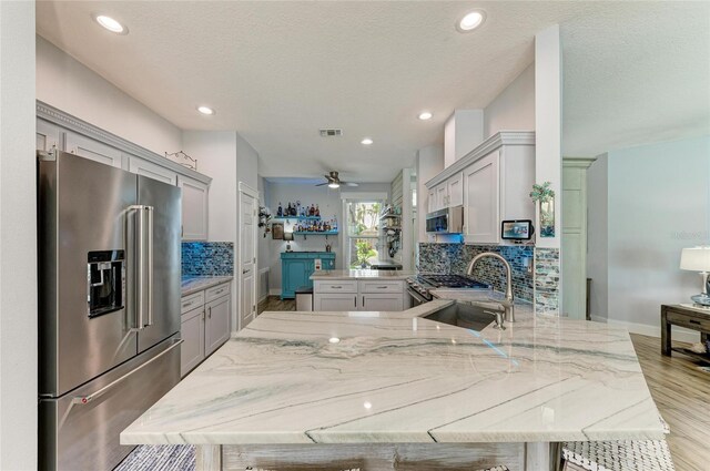220 39th St NE, Bradenton, FL 34208 - kitchen with appliances with stainless steel finishes, a peninsula, backsplash, light stone countertops, and recessed lighting