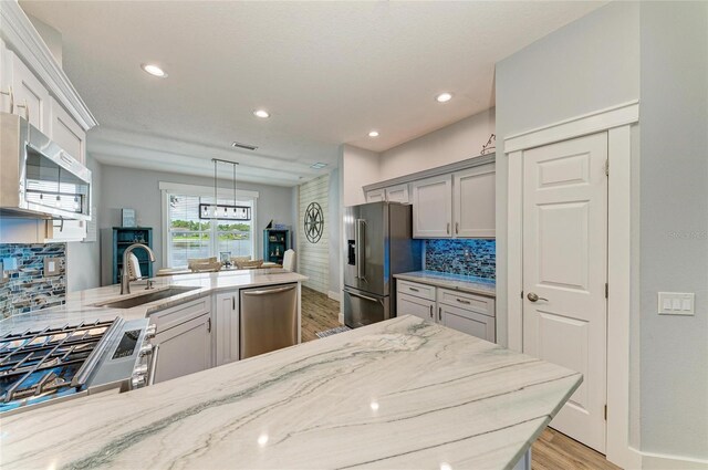 220 39th St NE, Bradenton, FL 34208 - kitchen with stainless steel appliances, light wood finished floors, backsplash, light stone counters, and recessed lighting