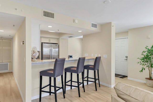 1240 Siesta Bayside Dr Unit 1240C, Sarasota, FL 34242 - kitchen featuring freestanding refrigerator, light wood-type flooring, a breakfast bar, a peninsula, and recessed lighting