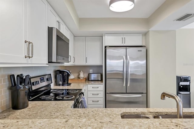 1240 Siesta Bayside Dr Unit 1240C, Sarasota, FL 34242 - kitchen featuring appliances with stainless steel finishes, white cabinets, decorative backsplash, and light stone countertops