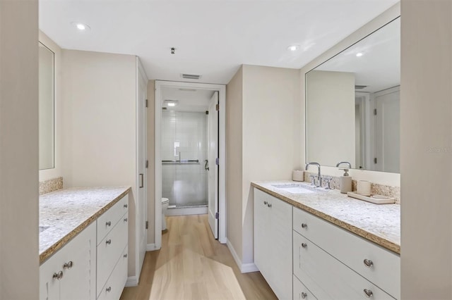 1240 Siesta Bayside Dr Unit 1240C, Sarasota, FL 34242 - bathroom featuring two vanities, wood finished floors, a stall shower, and recessed lighting
