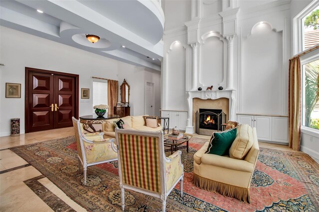 550 Dove Pointe, Osprey, FL 34229 - living room with inlaid floor details, a premium fireplace, a towering ceiling, decorative columns, and recessed lighting