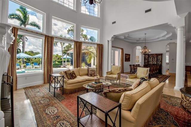 550 Dove Pointe, Osprey, FL 34229 - living area with decorative columns, a chandelier, a raised ceiling, and a towering ceiling