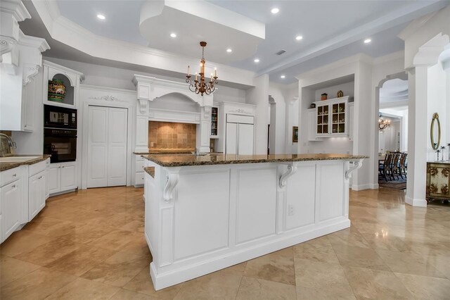 550 Dove Pointe, Osprey, FL 34229 - kitchen featuring a chandelier, glass insert cabinets, paneled built in fridge, a breakfast bar area, and ornamental molding