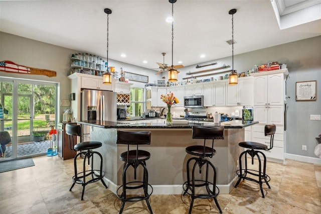 15780 Wilson Rd, Sarasota, FL 34240 - kitchen featuring stainless steel appliances, dark countertops, white cabinetry, a breakfast bar area, and recessed lighting