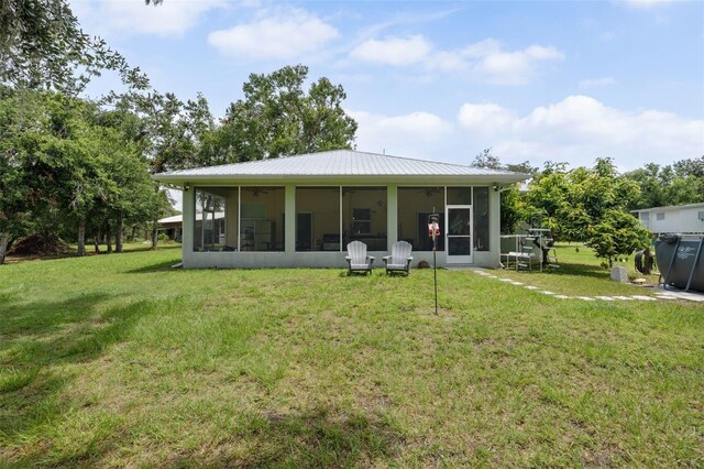 15780 Wilson Rd, Sarasota, FL 34240 - back of house with a sunroom, a lawn, a ceiling fan, and a metal roof