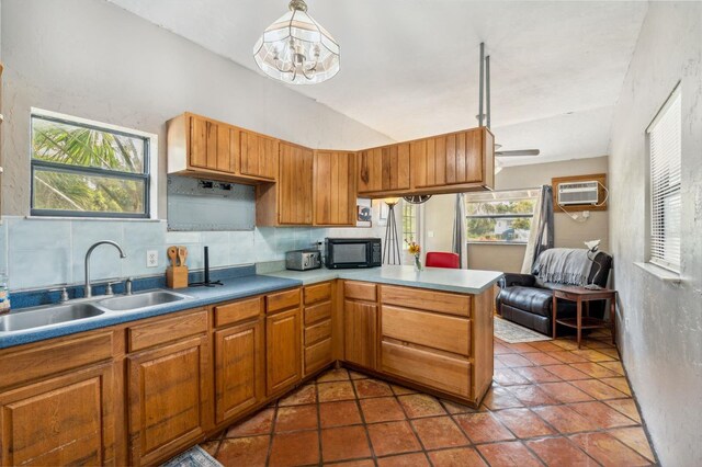 15780 Wilson Rd, Sarasota, FL 34240 - kitchen featuring black microwave, backsplash, a peninsula, a wall unit AC, and brown cabinets