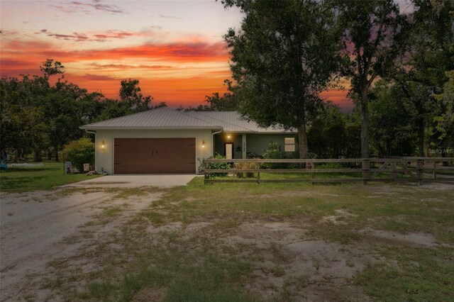 15780 Wilson Rd, Sarasota, FL 34240 - view of front of property with dirt driveway, an attached garage, stucco siding, a metal roof, and a standing seam roof