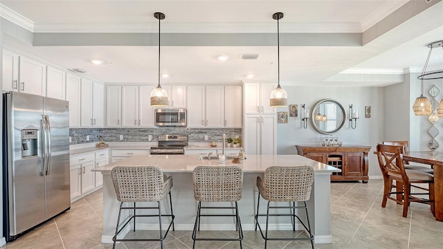 1030 Tidewater Shores Loop Unit 307, Bradenton, FL 34208 - kitchen featuring stainless steel appliances, tasteful backsplash, white cabinetry, a kitchen island with sink, and light countertops