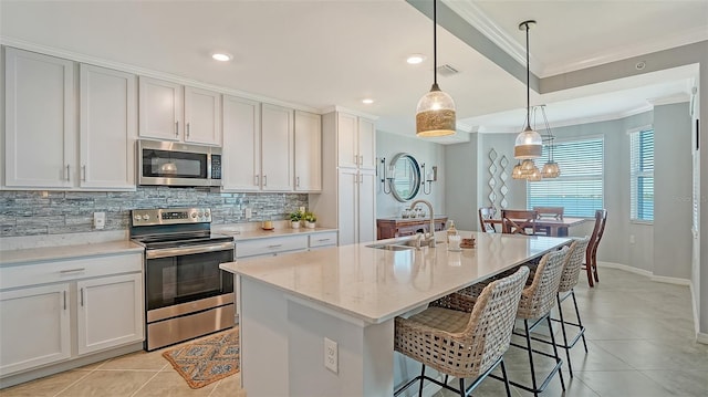 1030 Tidewater Shores Loop Unit 307, Bradenton, FL 34208 - kitchen featuring stainless steel appliances, crown molding, backsplash, light tile patterned floors, and an island with sink