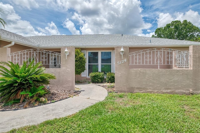 5124 Palm Aire Dr, Sarasota, FL 34243 - property entrance featuring stucco siding, a yard, and roof with shingles