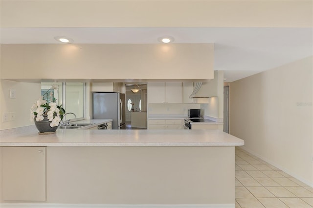 5124 Palm Aire Dr, Sarasota, FL 34243 - kitchen with freestanding refrigerator, light countertops, a peninsula, light tile patterned floors, and recessed lighting