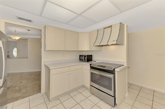 5124 Palm Aire Dr, Sarasota, FL 34243 - kitchen with appliances with stainless steel finishes, cream cabinets, range hood, light countertops, and light tile patterned floors