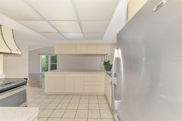 5124 Palm Aire Dr, Sarasota, FL 34243 - kitchen with appliances with stainless steel finishes, extractor fan, light countertops, light tile patterned flooring, and a paneled ceiling