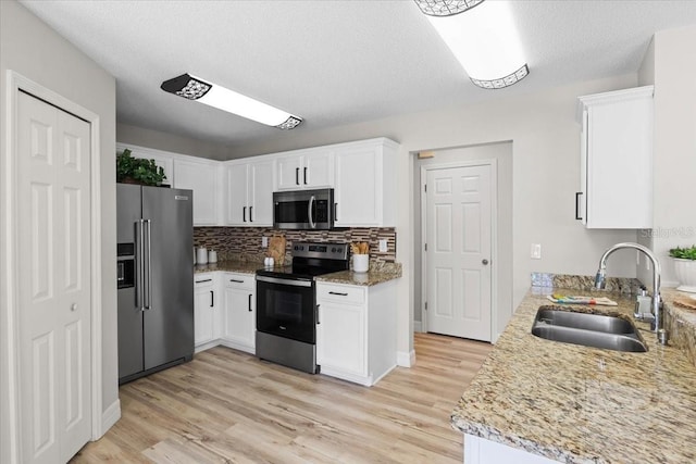 11839 Shrewsbury Ln, Parrish, FL 34219 - kitchen featuring stainless steel appliances, light wood-style floors, white cabinetry, backsplash, and a textured ceiling
