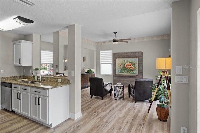 11839 Shrewsbury Ln, Parrish, FL 34219 - kitchen with stainless steel dishwasher, light wood-style floors, light stone counters, white cabinets, and open floor plan