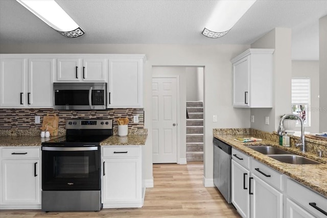 11839 Shrewsbury Ln, Parrish, FL 34219 - kitchen with appliances with stainless steel finishes, white cabinets, light wood-type flooring, light stone counters, and backsplash