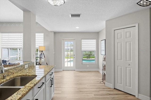 11839 Shrewsbury Ln, Parrish, FL 34219 - kitchen with light wood-style flooring, a textured ceiling, light stone countertops, and white cabinets