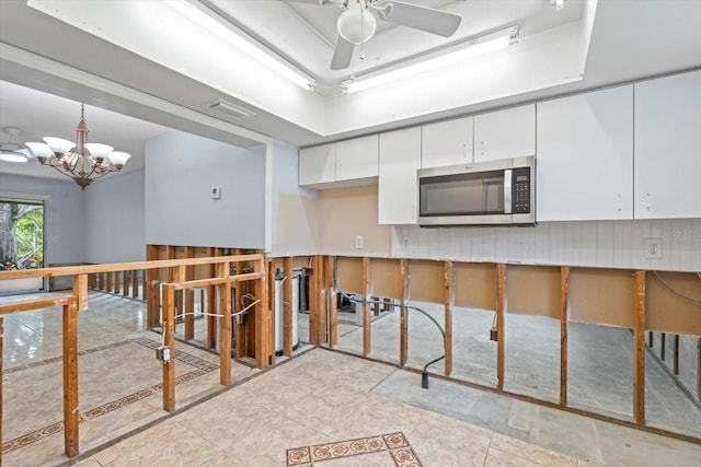 2115 9th Ave W Unit 3D, Bradenton, FL 34205 - kitchen with stainless steel microwave, white cabinets, a ceiling fan, a chandelier, and light tile patterned flooring
