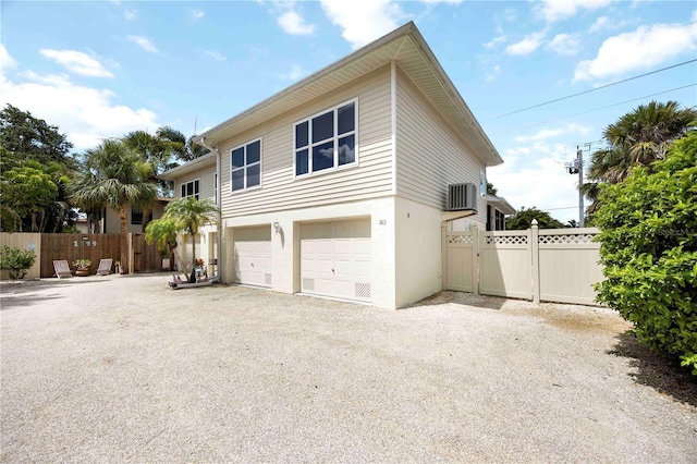 1801 Highland Rd, Osprey, FL 34229 - view of side of property with an attached garage, gravel driveway, stucco siding, and a gate