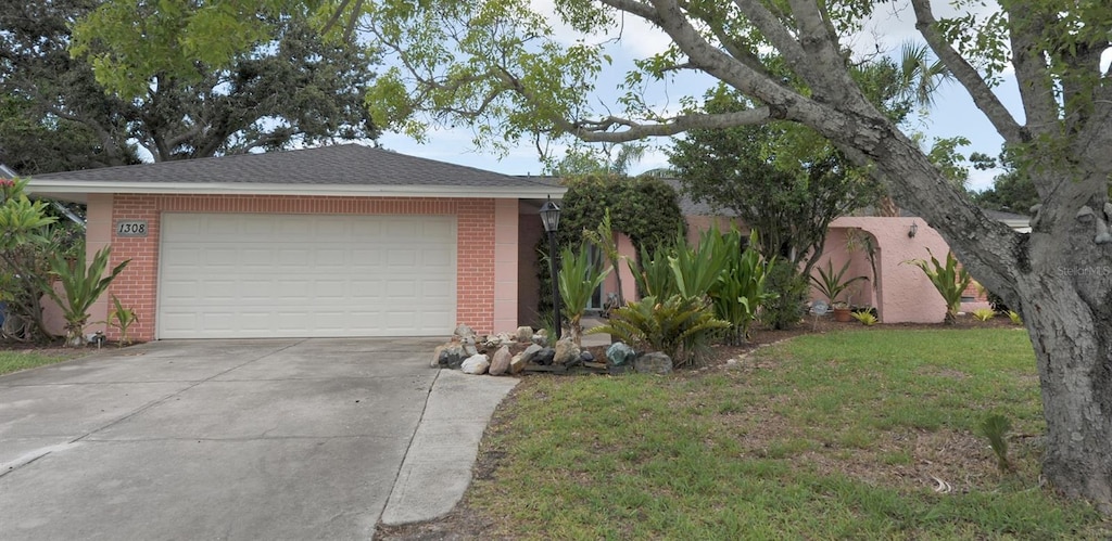 1308 63rd St NW, Bradenton, FL 34209 - view of front of property featuring brick siding, driveway, an attached garage, and a front lawn