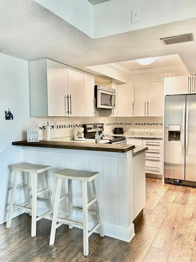 21405 Olean Blvd Unit 224, Port Charlotte, FL 33952 - kitchen featuring stainless steel appliances, light wood-style floors, tasteful backsplash, a peninsula, and a textured ceiling