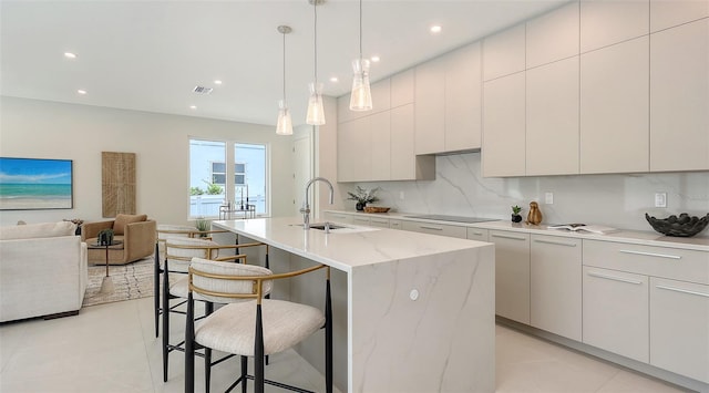 2590 Floyd St, Sarasota, FL 34239 - kitchen featuring a kitchen breakfast bar, tasteful backsplash, open floor plan, black electric cooktop, and a center island with sink