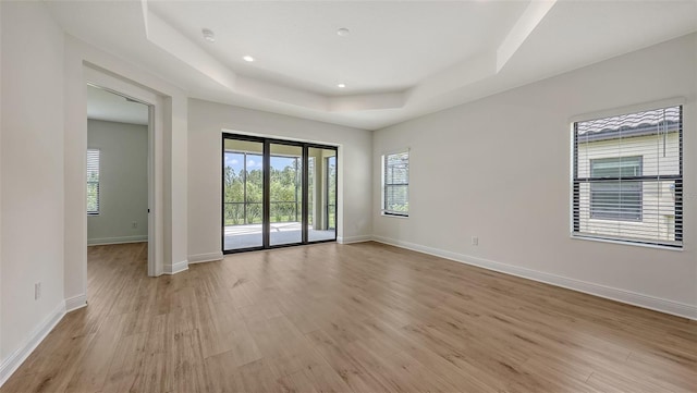 248 Altamura Cir, Nokomis, FL 34275 - empty room featuring a tray ceiling, light wood-type flooring, plenty of natural light, a smoke detector, and recessed lighting