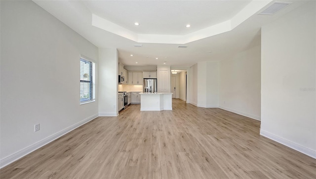248 Altamura Cir, Nokomis, FL 34275 - unfurnished living room with light wood-style flooring, recessed lighting, and a tray ceiling
