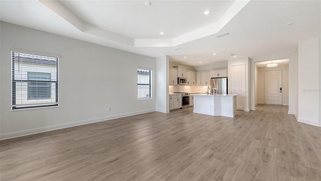 248 Altamura Cir, Nokomis, FL 34275 - unfurnished living room featuring a raised ceiling, light wood-style flooring, and recessed lighting