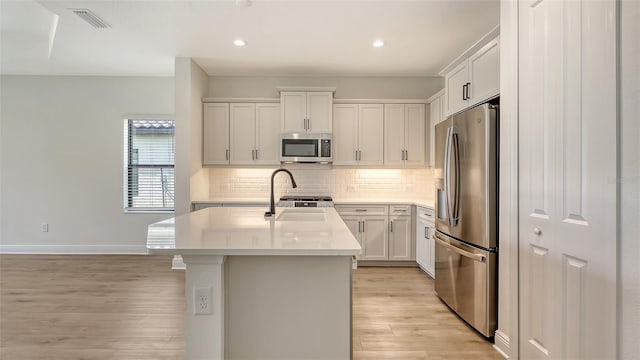 248 Altamura Cir, Nokomis, FL 34275 - kitchen featuring stainless steel appliances, light wood-style flooring, a center island with sink, light countertops, and recessed lighting