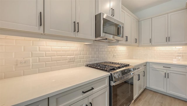 248 Altamura Cir, Nokomis, FL 34275 - kitchen featuring appliances with stainless steel finishes, light countertops, backsplash, light wood-style flooring, and white cabinets