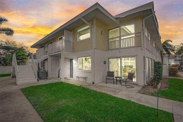 999 Inlet Cir Unit 103, Venice, FL 34285 - back of property at dusk with a lawn, stairs, a patio, and stucco siding