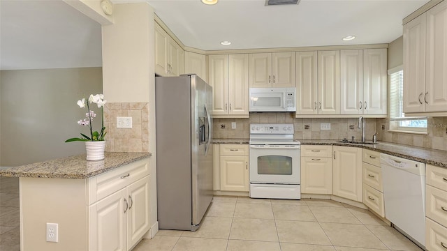 2088 Grove St, Sarasota, FL 34239 - kitchen with white appliances, light tile patterned floors, tasteful backsplash, light stone countertops, and a peninsula