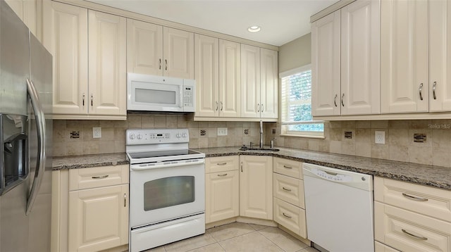 2088 Grove St, Sarasota, FL 34239 - kitchen with white appliances, decorative backsplash, light tile patterned floors, recessed lighting, and dark stone countertops