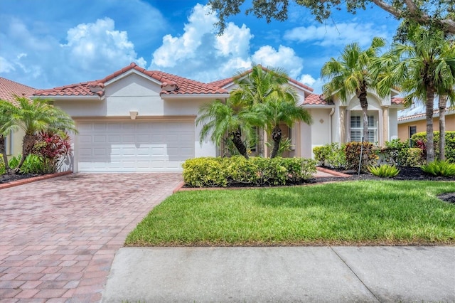6312 41st Ct E, Sarasota, FL 34243 - mediterranean / spanish-style home with decorative driveway, an attached garage, stucco siding, a front yard, and a tiled roof