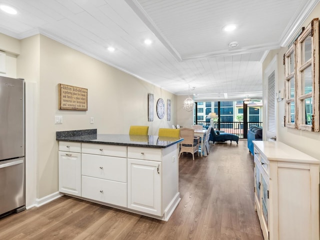 8710 Midnight Pass Rd Unit 205, Sarasota, FL 34242 - kitchen with freestanding refrigerator, a peninsula, crown molding, wood finished floors, and white cabinetry