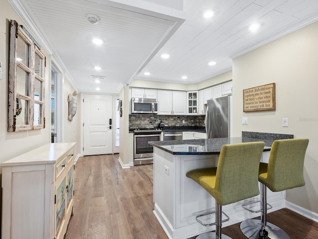 8710 Midnight Pass Rd Unit 205, Sarasota, FL 34242 - kitchen featuring stainless steel appliances, a peninsula, a kitchen breakfast bar, glass insert cabinets, and wood finished floors