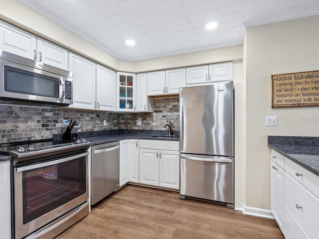 8710 Midnight Pass Rd Unit 205, Sarasota, FL 34242 - kitchen featuring appliances with stainless steel finishes, decorative backsplash, white cabinetry, ornamental molding, and light wood-style floors