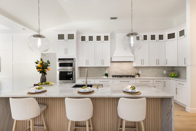 7211 Marston Ct, University Park, FL 34201 - kitchen with stainless steel appliances, tasteful backsplash, light wood-style flooring, white cabinetry, and lofted ceiling