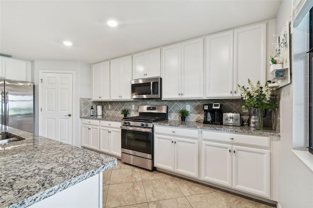 5916 Wake Forest Run Unit 101, Bradenton, FL 34211 - kitchen featuring appliances with stainless steel finishes, backsplash, light tile patterned floors, white cabinetry, and recessed lighting
