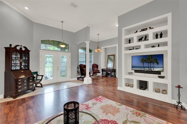17426 Tailfeather Ct, Clermont, FL 34711 - living room featuring arched walkways, french doors, built in shelves, wood finished floors, and decorative columns