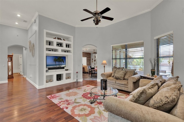 17426 Tailfeather Ct, Clermont, FL 34711 - living area featuring arched walkways, built in features, a ceiling fan, crown molding, and wood finished floors