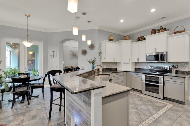 17426 Tailfeather Ct, Clermont, FL 34711 - kitchen with appliances with stainless steel finishes, arched walkways, decorative backsplash, dark stone counters, and crown molding