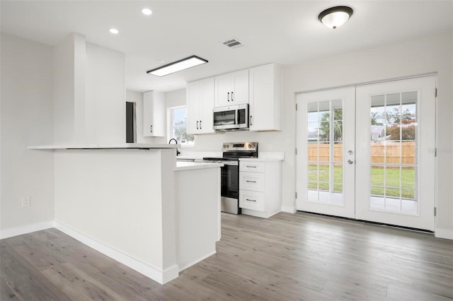 609 Carmel Rd, Venice, FL 34293 - kitchen with stainless steel appliances, french doors, light wood-style floors, white cabinetry, and recessed lighting